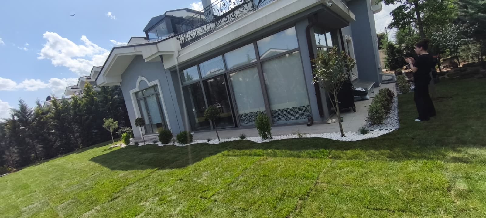 Müstakil ev önünde çim alan ve bitki kuşağıyla düzenlenmiş ön bahçe