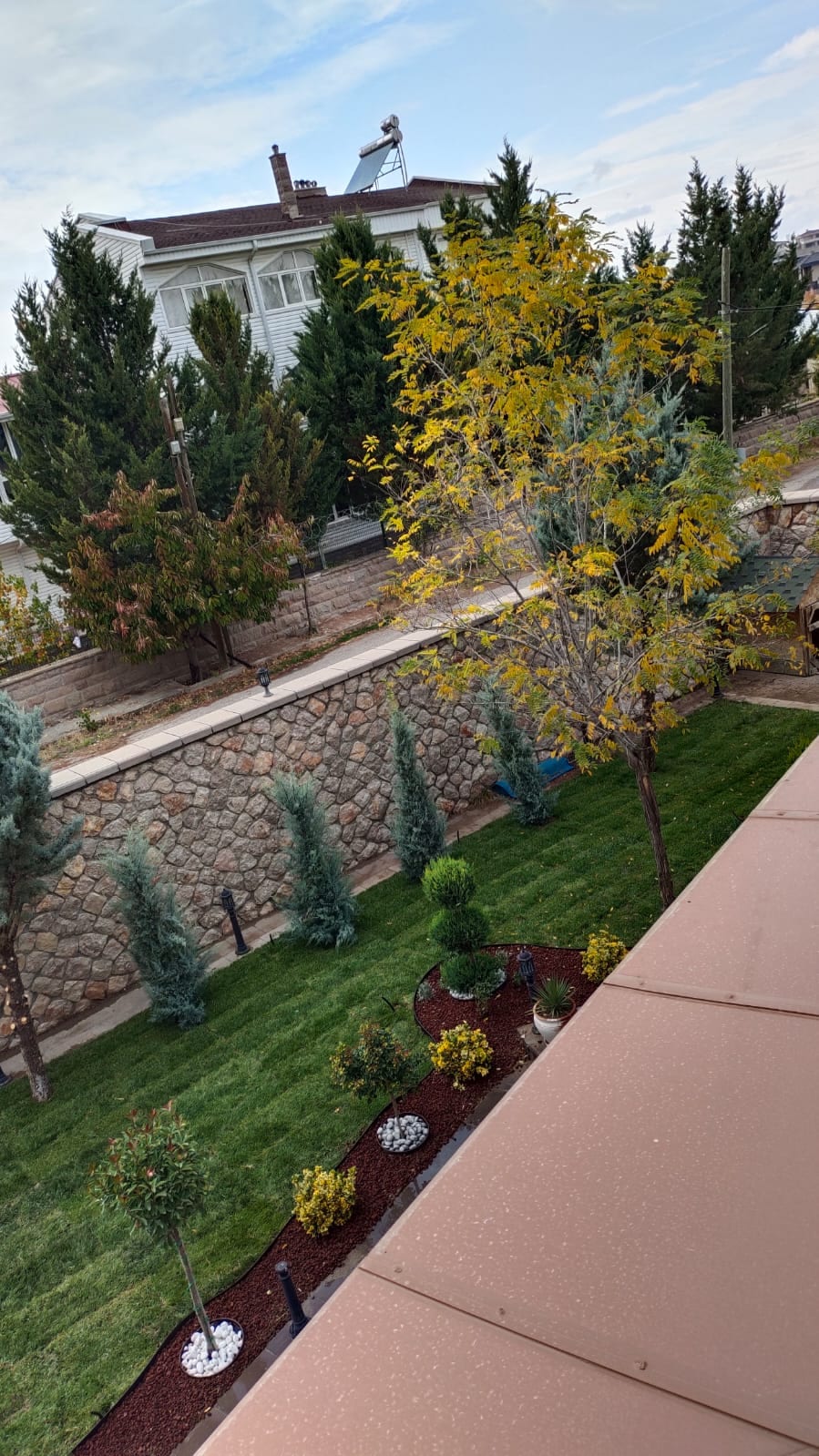 Ankara'da sonbahar sonu bir bahçe: taş duvar önünde çim alanın mevsimsel görünümü