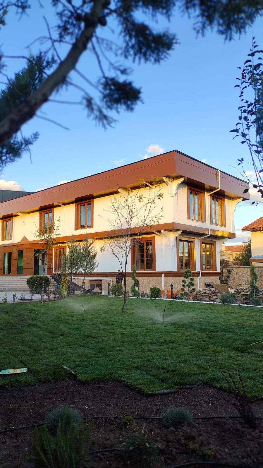 Villa bahçesinde akşam saatinde çalışan otomatik sulama sistemi